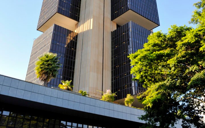Fachada da sede do Banco Central em Brasília, com palmeiras à frente.