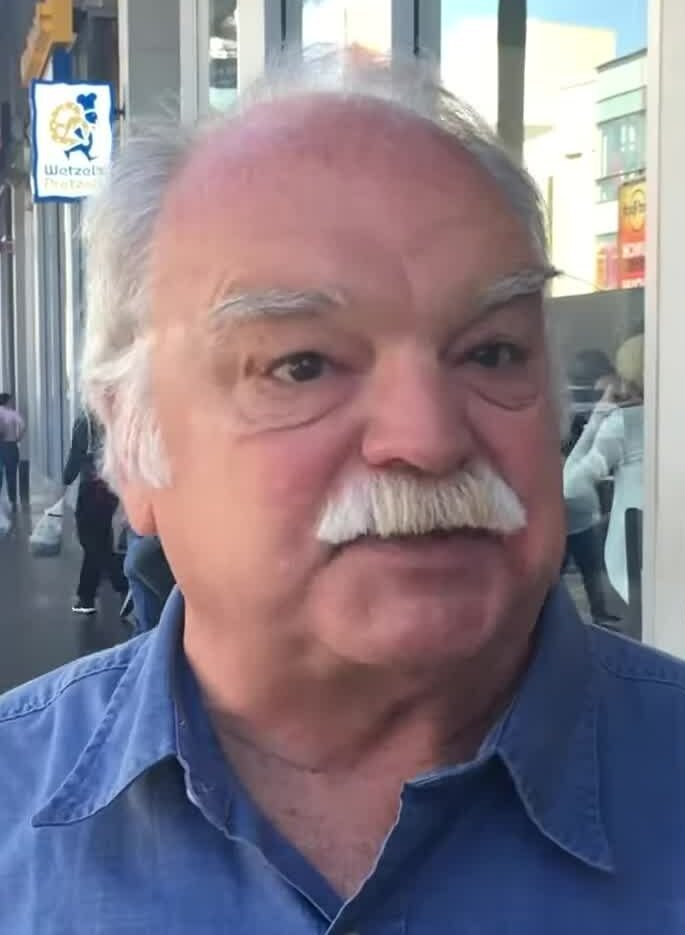 Richard Riehle, de camisa azul e bigode branco, em registro de 2016